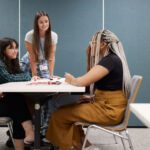 Students sitting around a desk talking together