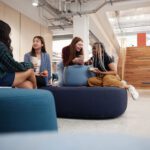 Students sitting on casual furniture in the library foyer chatting.