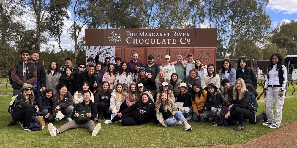 FBL International students take a group photo in front of the Margaret River Chocolate Factory sign.