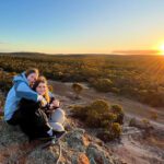 Two students embracing while the sun rises.