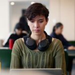 Student wearing a green jumper and headphones