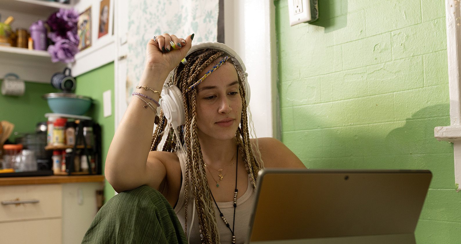 A student with headphones observing something on her laptop.