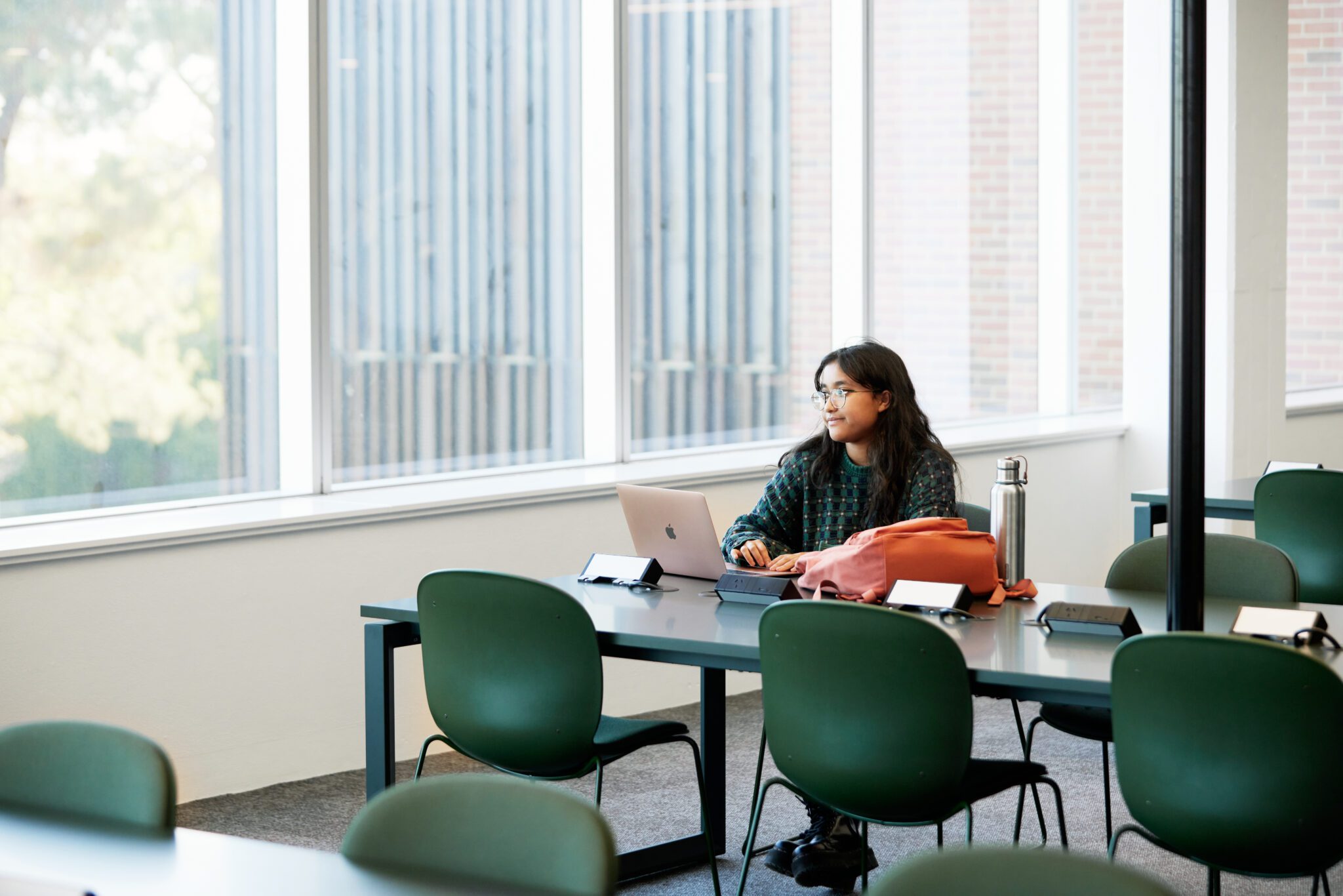 Student studying in the curtin library, smiling out the window