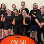 Group of students wearing black and holding orange water bottles.