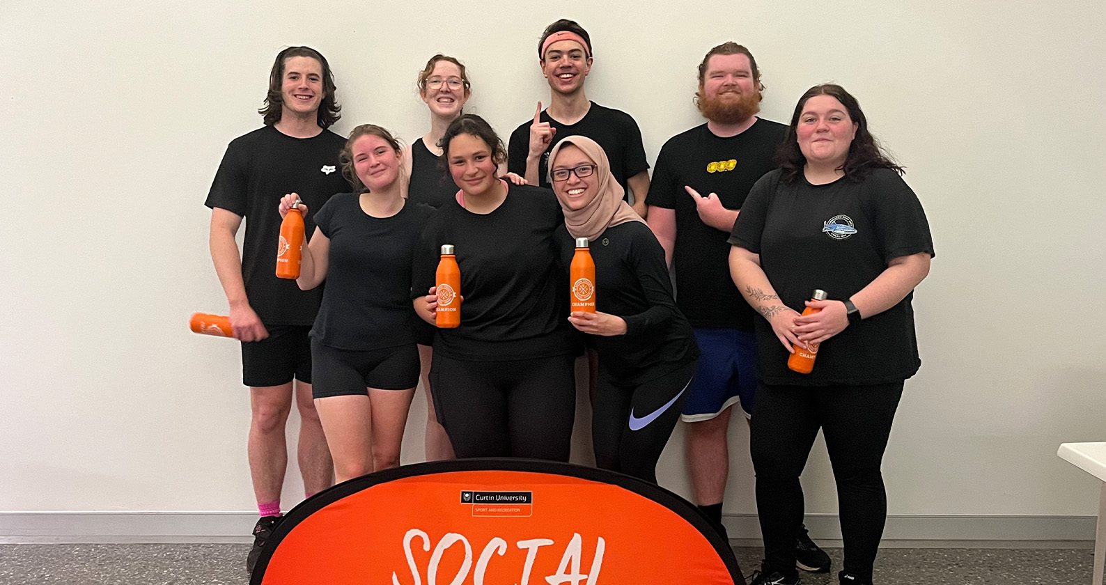 Group of students wearing black and holding orange water bottles.