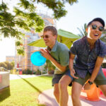 Two students laughing and playing frisbee on campus