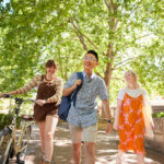 Three students walking on campus with greenery in the background.