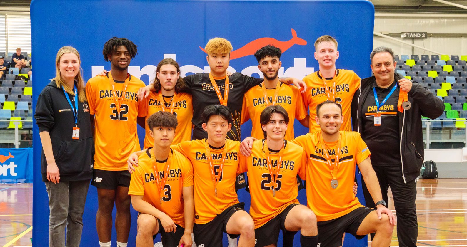 A group of University students and Curtin Carnaby UniSports representatives stand and kneel for a photo.