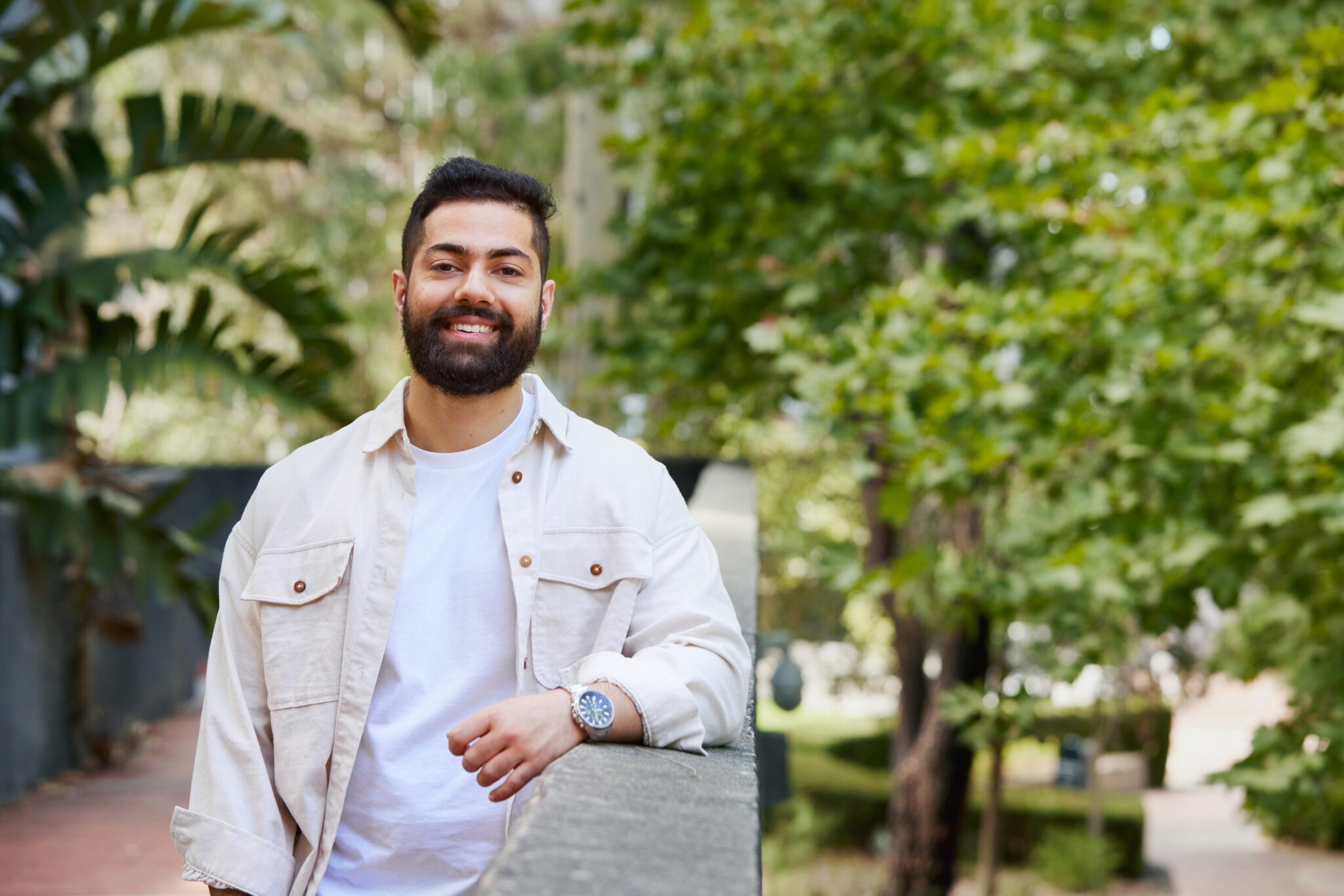 Student wearing a white button up shirt, leaning on a wall