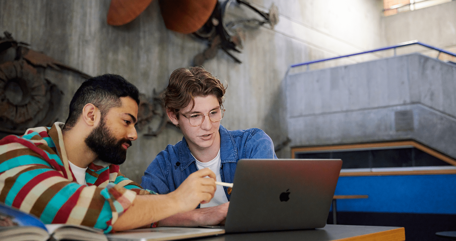 Two students looking at a grey laptop.