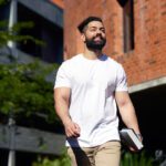 Student wearing a white shirt walking through campus