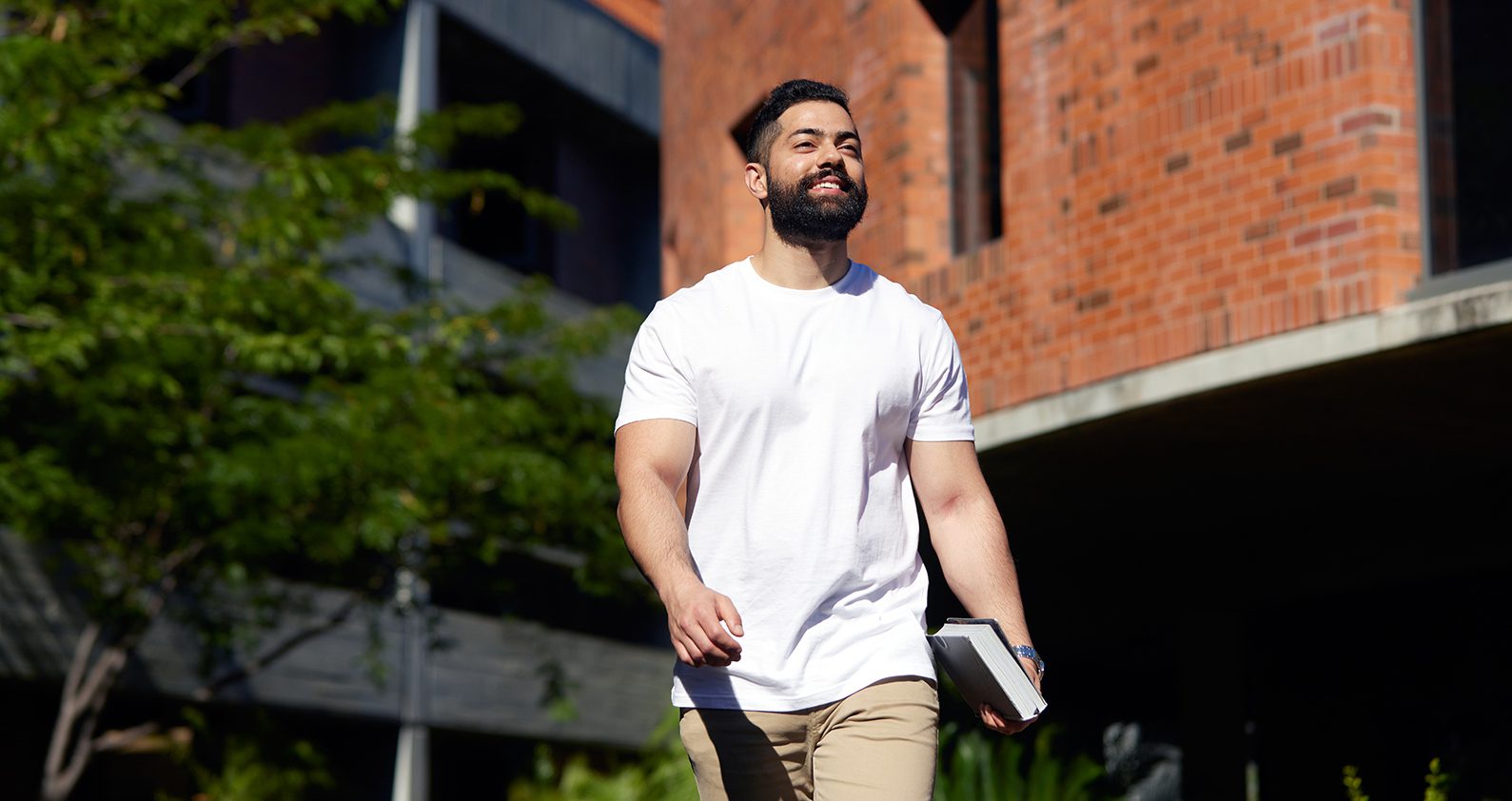 Student wearing a white shirt walking through campus