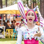 A street performer juggles bowling pins while another performer watches.