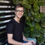 A student is sitting on a bench with his laptop.