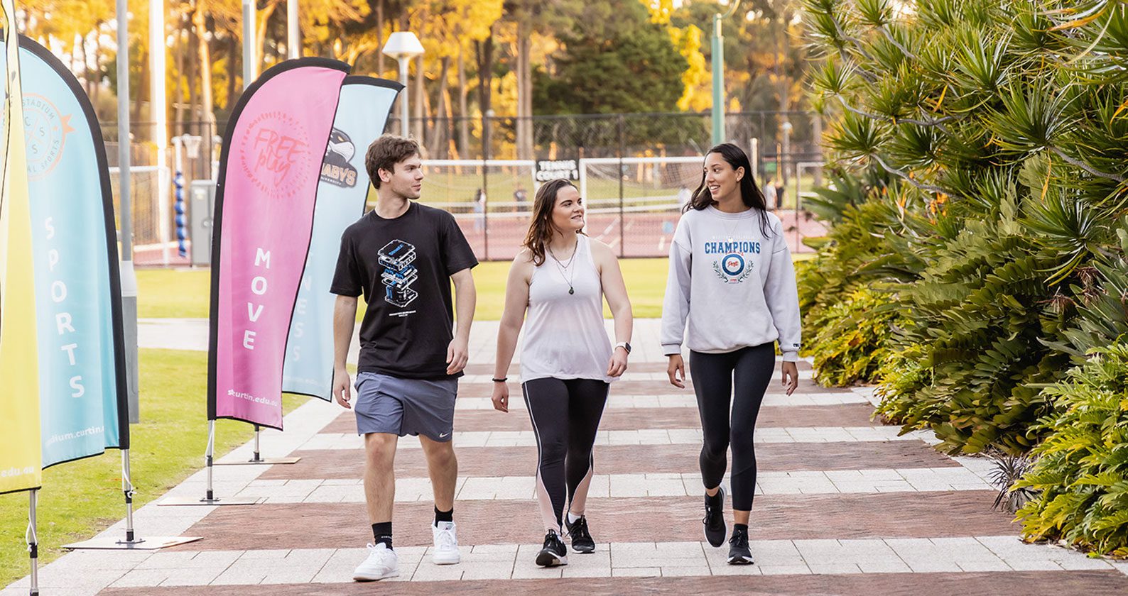 Three students walking along a path at Curtin Stadium.