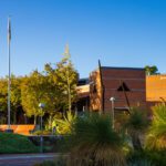 A blue sky over a building and the flagpoles on the Curtin Perth campus.