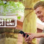 A student smiling at his phone with the Respect at Uni logo.