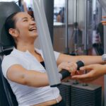 Celena is laughing while on a gym machine. She wears workout gear.