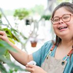 A woman with down syndrome working in a gardening greenhouse and smiling.