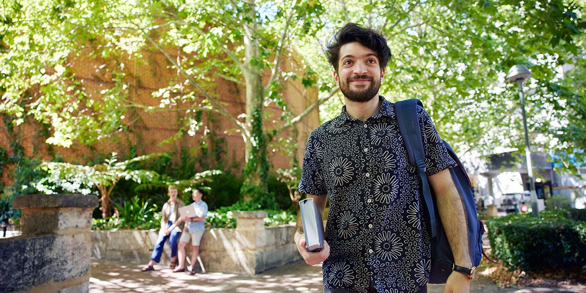 student walking on campus with book