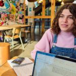 Young girl sitting at desk talking to someone with computer