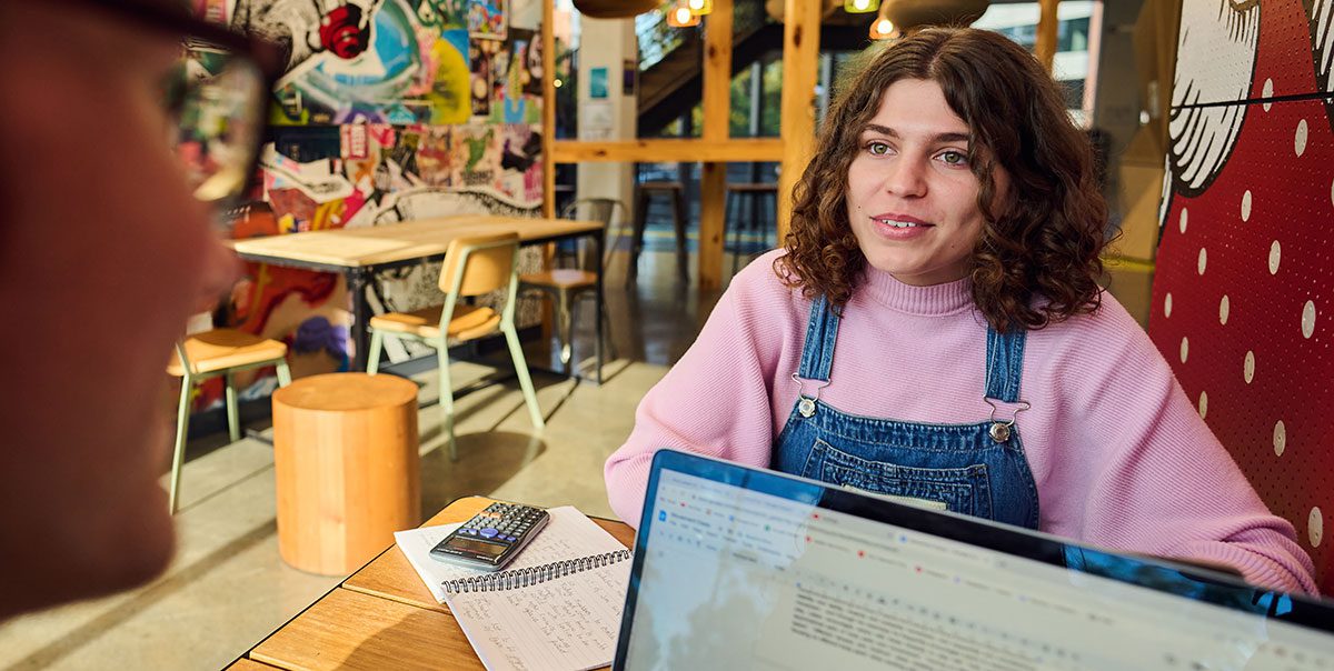 Young girl sitting at desk talking to someone with computer