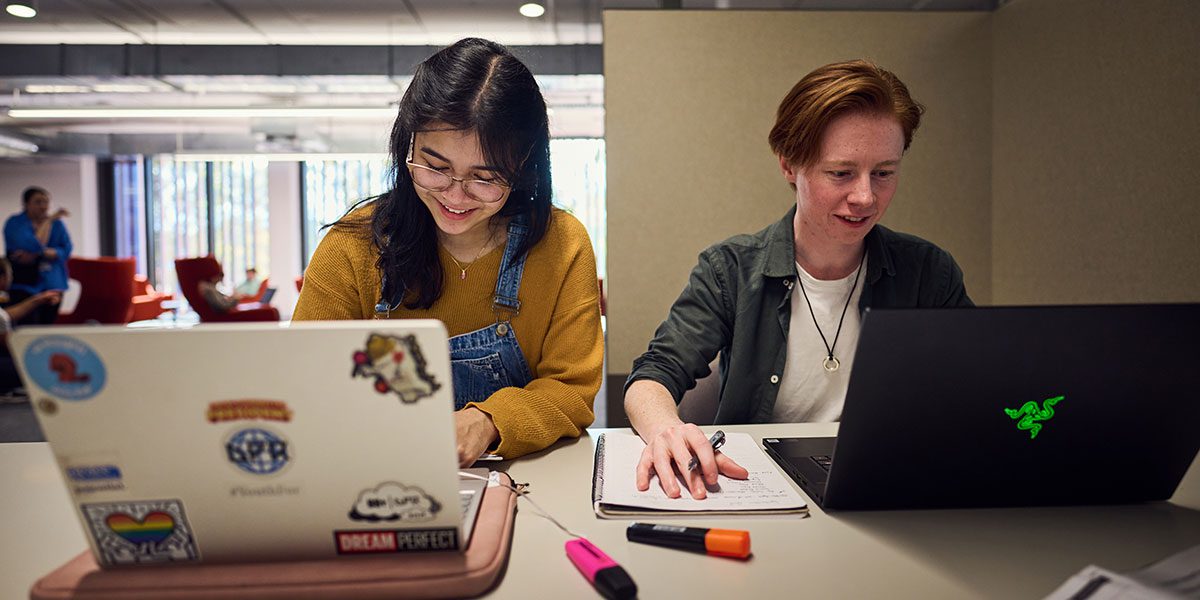 Two students sitting at computers on desk