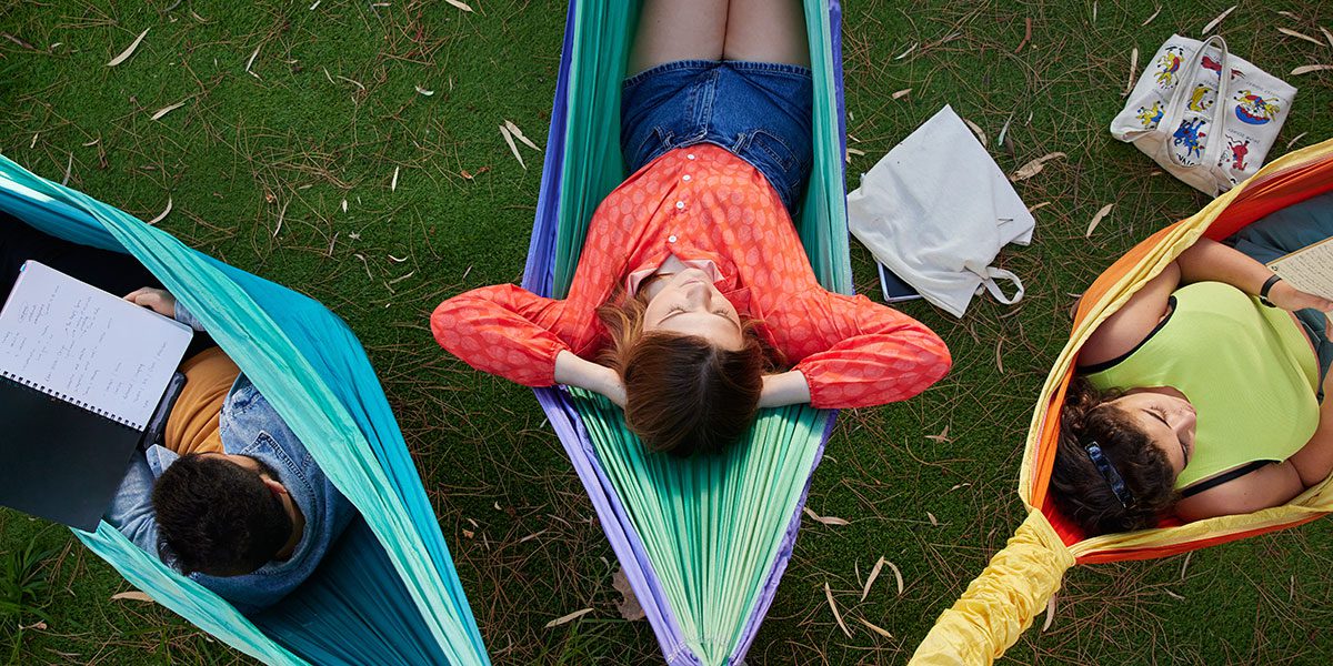 Three students lying down in hammocks