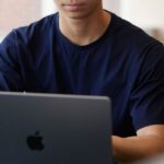 A male student typing on an Apple MacBook.