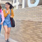 Two girls walking and laughing through campus