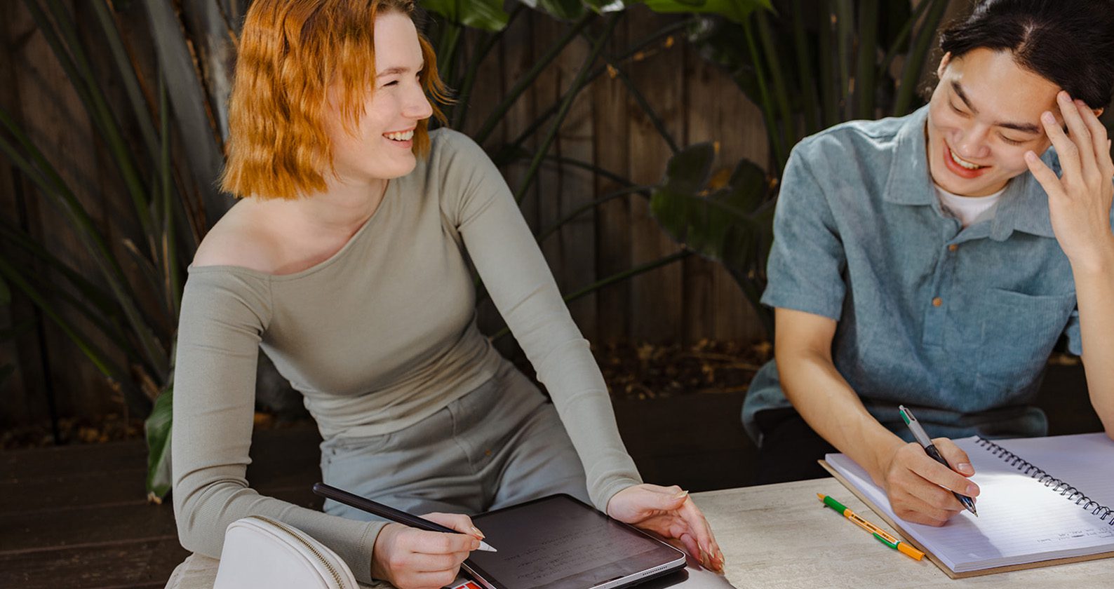 Two students sitting at a table, laughing and studying