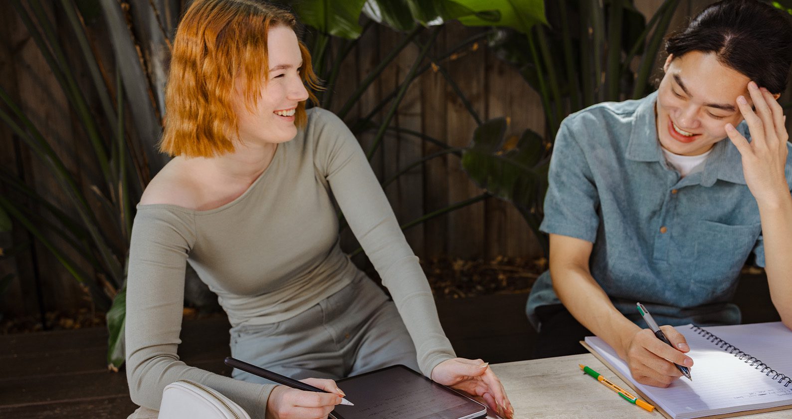 Two students laughing while studying outdoors.