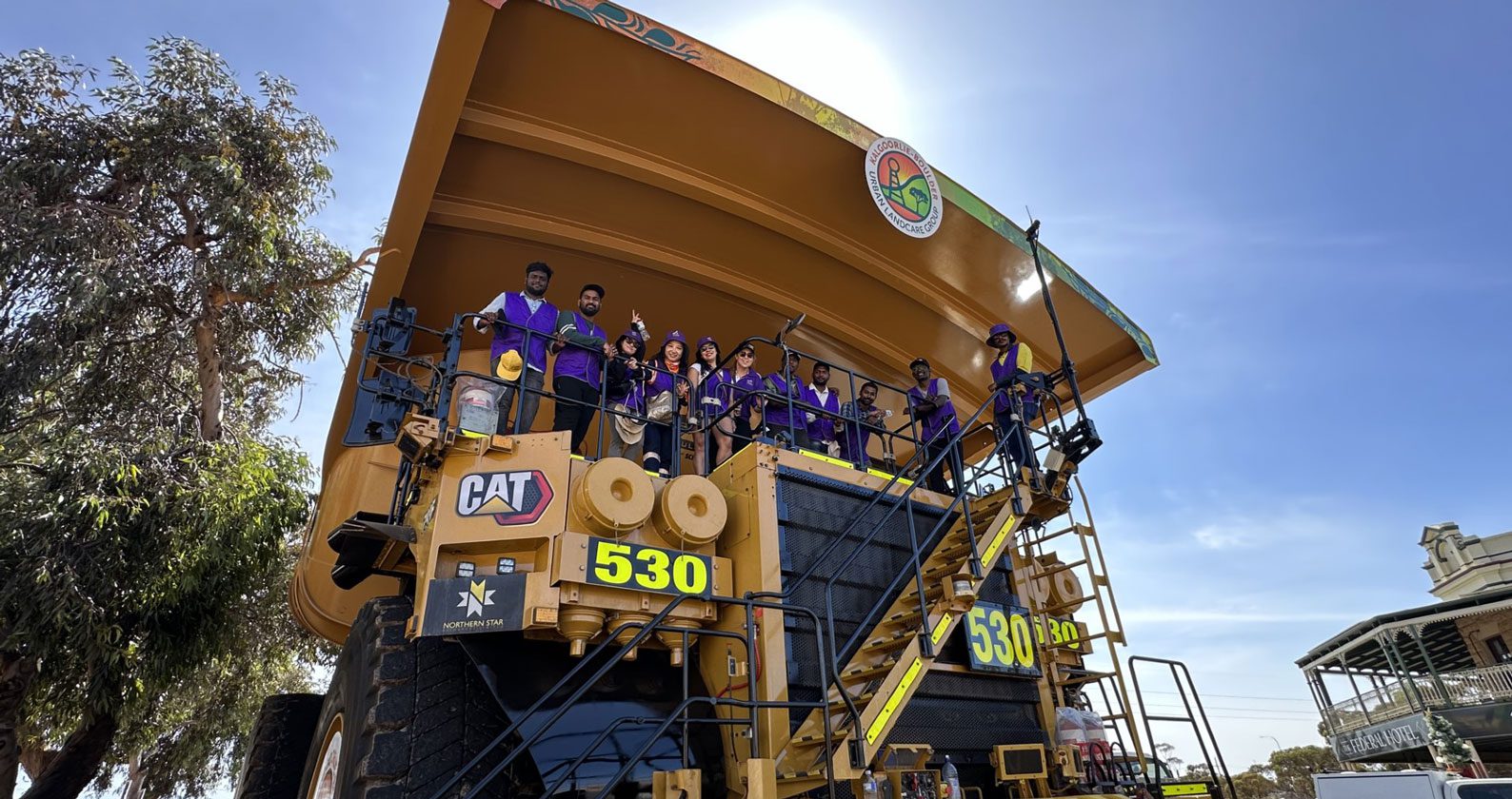 A large mining truck with students posing for a photo at its helm.