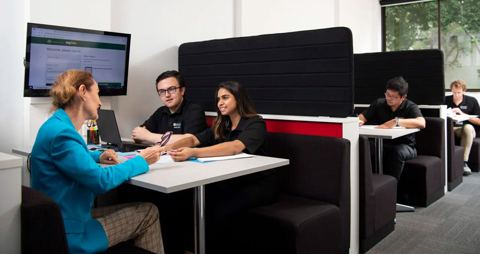 A group of booths with students and staff sitting in each one.