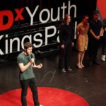 Image of a person talking on stage at the Tedx Youth @ Kingspark show.