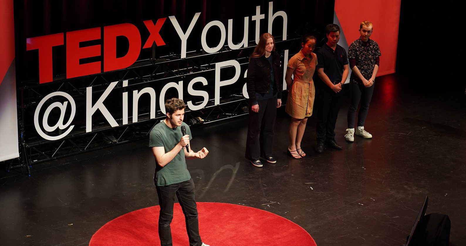 Image of a person talking on stage at the Tedx Youth @ Kingspark show.