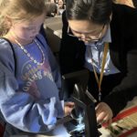 A child and adult use a microscope together.