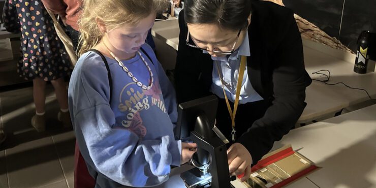 A child and adult use a microscope together.