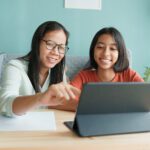 A mum and daughter look at a tablet together.