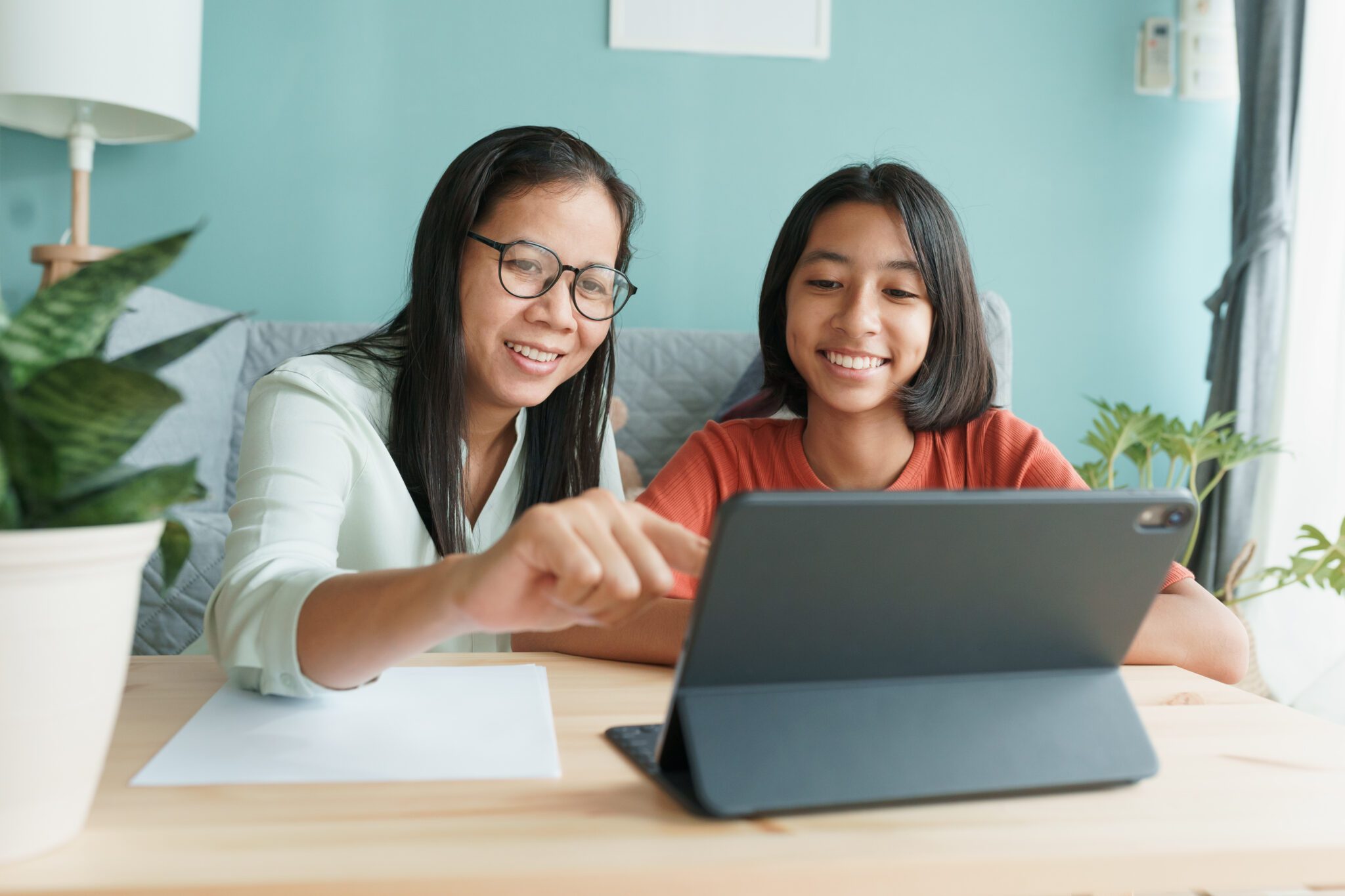 A mum and daughter look at a tablet together.