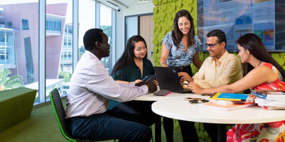 Five Curtin University students working together around a desk on the Bentley (Perth) Campus