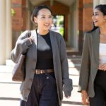 Two women in suits laughing.