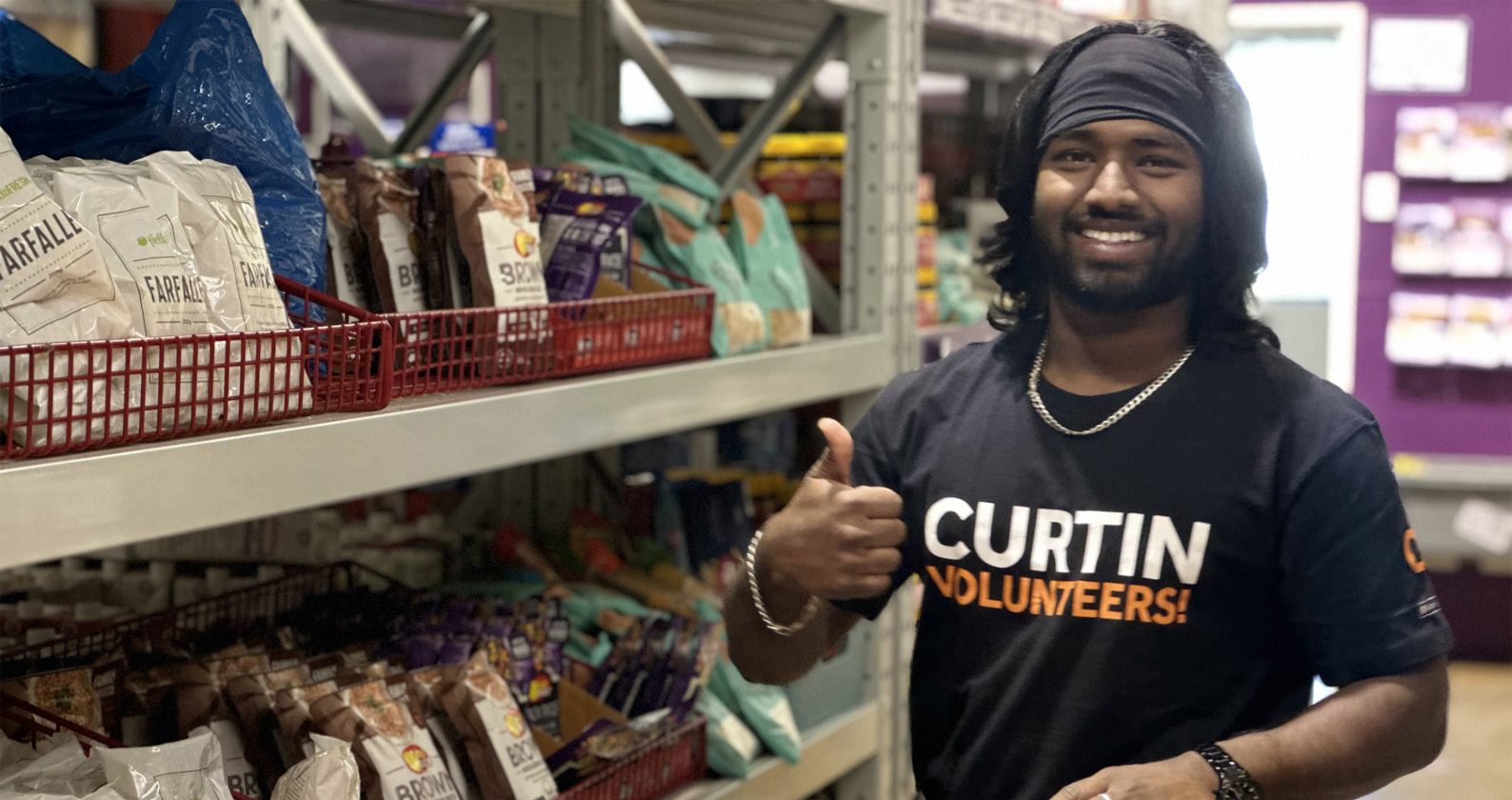 Curtin Kalgoorlie student and Curtin Volunteer! gives a thumbs up to the camera whilst working at Food Bank.