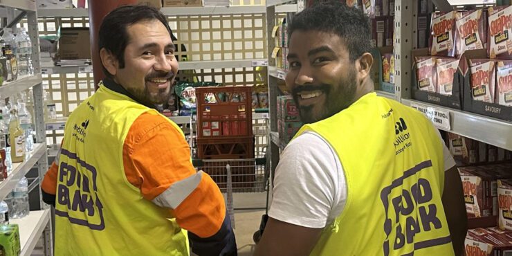 Two Curtin Volunteers! smile with a hi-vis food bank vest on