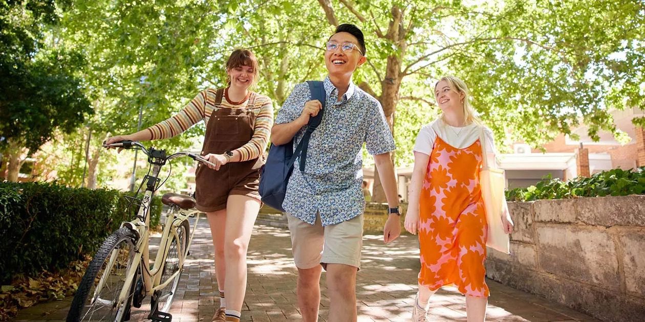 Three Curtin University students walking on campus and smiling.