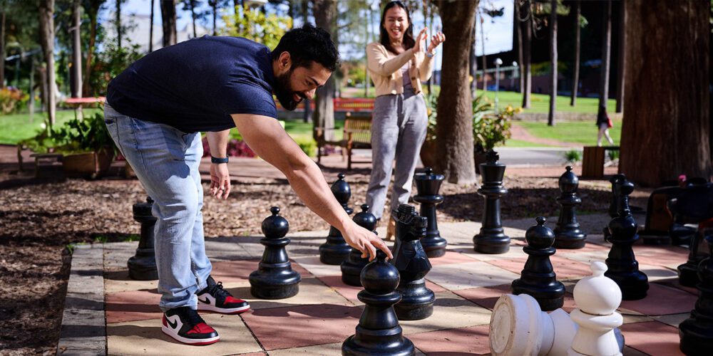 Two Curtin University students playing a game of jumbo chess at the Pines in Henderson.