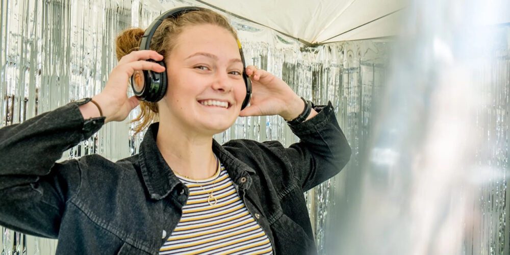 Curtin University student enjoying the campus life. They are smiling and wearing headphones. 
