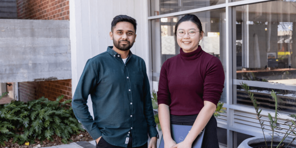 Two university students standing at the Curtin University Perth campus and smiling to camera.