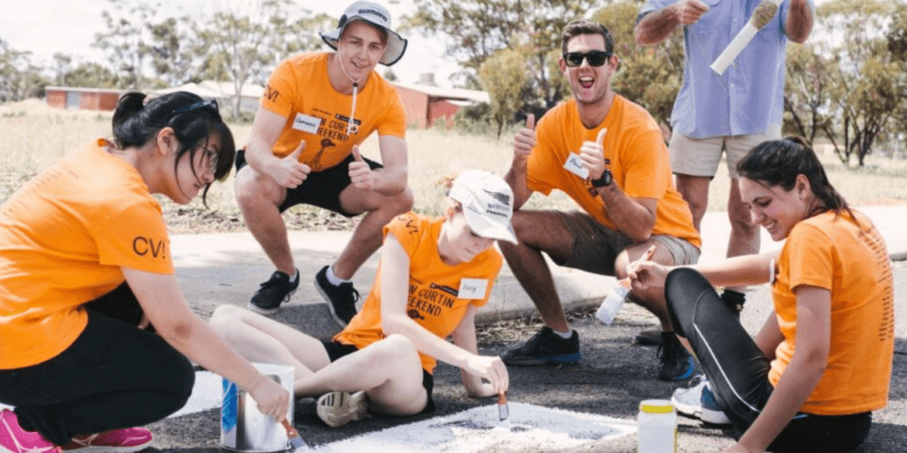 Five Curtin Volunteers! working on a project together, and smiling.