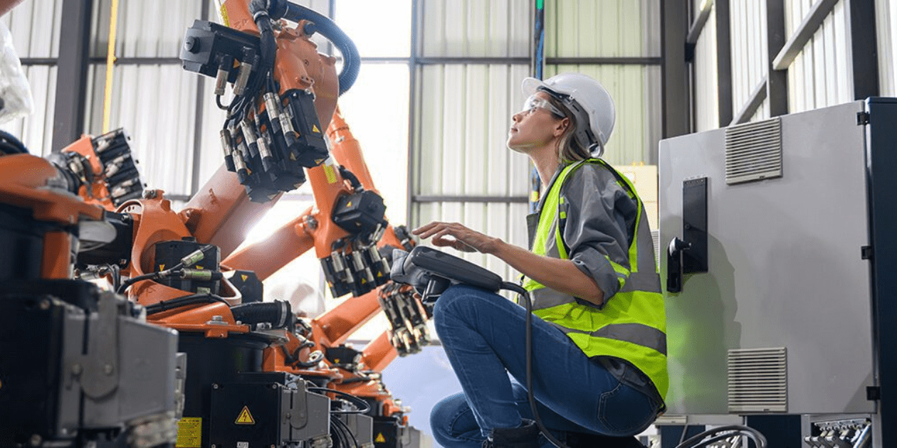A Curtin University student in high-visibility clothing, looking at a machine.